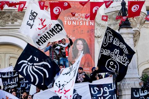 January 14, 2015: About 50 young Islamists from the Kram League for the Protection of the Revolution came to wave banners reading “I am not Charlie” or “I am Muhammad.” Tunisians gathered on Habib Bourguiba Avenue in Tunis to celebrate the fourth anniversary of the Tunisian revolution, which led to the ouster of former President Zine el Abdidine Ben Ali on Friday, January 14, 2011, and his exile to Saudi Arabia. Among the many Tunisians who came to march with their families under mild sunshine, a wide variety of groups were scattered along the avenue: families of martyrs, supporters of Hizb ut-Tahrir, Ennahda, or El Watan, Islamist youth from the LPR, and supporters of Sofiane and Nadhir, ...