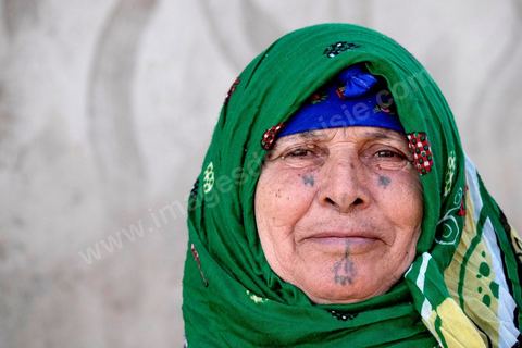 27 janvier 2016 : Portrait de femme traditionnelle tatouée. Quartier populaire et deshérité de Karma sur les hauteurs de Kasserine. Ici la population vit au milieu des poubelles, construisent leurs maison de façon anarchiques jusque dans les oueds. Les familles vivent entassés dans des maisons certes en dure mais dans la plus grande précarité, pas de fenêtres, pas de portes, pas de chauffage et d'eau pour certains. Le seul terrain de jeu des enfants est les poubelles. 