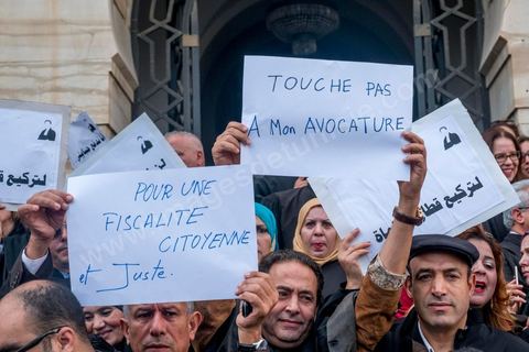 6 décémbre 2016 : Plus de 2.000 avocats ont manifesté mardi à Tunis contre les nouvelles dispositions fiscales qui leur ont été imposées dans le projet de budget 2017, actuellement examiné par le Parlement."Avec notre âme, avec notre sang nous défendrons le métier d'avocat", ont crié les manifestants en robe noire devant le siège du gouvernement à la Kasbah, dans le centre de Tunis, après une marche de quelques centaines de mètres."Les avocats sont en colère!", "Nous n'allons pas financer votre corruption", pouvait-on lire sur des pancartes brandies par les protestataires, dont beaucoup jugent les nouvelles mesures "injustes" et "inapplicables".En cause, des taxes imposées pour chaque dossier traité, pouvant être déduites de l'impôt sur le revenu et prévues dans le projet de loi de finances 2017.Ce mouvement ne fait toutefois pas l'unanimité, et sur les réseaux sociaux comme dans certains médias, les protestations des avocats ont été considérées comme une volonté de bénéficier d'un traitement spécial. Selon le webzine Inkyfada, qui a analysé des données officielles, 60% des avocats enregistrés n'ont pas déclaré d'impôts en 2015, et "les avocats en règle paient en moyenne 228 dinars (92 euros) d'impôt sur le revenu par mois".