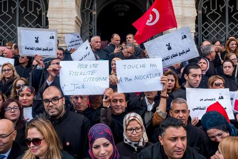 6 décémbre 2016 : Plus de 2.000 avocats ont manifesté mardi à Tunis contre les nouvelles dispositions fiscales qui leur ont été imposées dans le projet de budget 2017, actuellement examiné par le Parlement."Avec notre âme, avec notre sang nous défendrons le métier d'avocat", ont crié les manifestants en robe noire devant le siège du gouvernement à la Kasbah, dans le centre de Tunis, après une marche de quelques centaines de mètres."Les avocats sont en colère!", "Nous n'allons pas financer votre corruption", pouvait-on lire sur des pancartes brandies par les protestataires, dont beaucoup jugent les nouvelles mesures "injustes" et "inapplicables".En cause, des taxes imposées pour chaque dossier traité, pouvant être déduites de l'impôt sur le revenu et prévues dans le projet de loi de finances 2017.Ce mouvement ne fait toutefois pas l'unanimité, et sur les réseaux sociaux comme dans certains médias, les protestations des avocats ont été considérées comme une volonté de bénéficier d'un traitement spécial. Selon le webzine Inkyfada, qui a analysé des données officielles, 60% des avocats enregistrés n'ont pas déclaré d'impôts en 2015, et "les avocats en règle paient en moyenne 228 dinars (92 euros) d'impôt sur le revenu par mois".