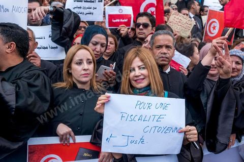 6 décémbre 2016 : Plus de 2.000 avocats ont manifesté mardi à Tunis contre les nouvelles dispositions fiscales qui leur ont été imposées dans le projet de budget 2017, actuellement examiné par le Parlement."Avec notre âme, avec notre sang nous défendrons le métier d'avocat", ont crié les manifestants en robe noire devant le siège du gouvernement à la Kasbah, dans le centre de Tunis, après une marche de quelques centaines de mètres."Les avocats sont en colère!", "Nous n'allons pas financer votre corruption", pouvait-on lire sur des pancartes brandies par les protestataires, dont beaucoup jugent les nouvelles mesures "injustes" et "inapplicables".En cause, des taxes imposées pour chaque dossier traité, pouvant être déduites de l'impôt sur le revenu et prévues dans le projet de loi de finances 2017.Ce mouvement ne fait toutefois pas l'unanimité, et sur les réseaux sociaux comme dans certains médias, les protestations des avocats ont été considérées comme une volonté de bénéficier d'un traitement spécial. Selon le webzine Inkyfada, qui a analysé des données officielles, 60% des avocats enregistrés n'ont pas déclaré d'impôts en 2015, et "les avocats en règle paient en moyenne 228 dinars (92 euros) d'impôt sur le revenu par mois".
