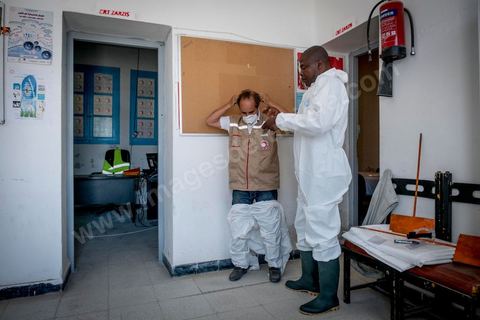 11 juin 2017 : Chemseddine Marzoug et Mohamed Trabelsi dans le local du croissant rouge tunisien de Zarzis s'équipent de leur tenue pour récupérer les corps de migrants. A Zarzis, sur le littoral tunisien, frontalier de la Libye, Chemseddine Marzoug, ancien pêcheur au chomage, offre bénévolement depuis 10 ans une sépulture de sable aux noyés de la Méditerranée. Bénévoles pour le croissant rouge tunisien Chemseddine et son collègue Mohamed Trabelsi enterrent depuis 10 ans les corps des migrants trouvés en mer ou échoués sur les plages du sud tunisien dans un cimetière improvisé dans une décharge municipale. En cette saison de printemps, les morts sont très nombreux 27 corps ont été repêchés ce dernier mois. 