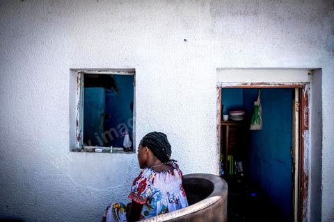 24 juin 2017 : Océane devant la cuisine qui donne sur la cour. Chez Océane, migrante Ivoirienne à Tunis dans un quartier populaire. Elle vit dans une maison avec 2 chambres qu'elle partage avec son fils Eden et cinq autres ivoiriennes. Océane est arrivée en Tunisie en 2010 comme étudiante et est depuis 5 ans en situation irrégulière, ne lui permettant plus de travailler légalement. Il y a deux ans Eden est né, ce jeune garçon plein de joie est devenu sa raison de vivre, elle souhaite trouver un endroit pour vivre normalement et élever son fils. “J’estime que pour vivre bien Tunisie, il me faudrait entre 800 et 1000 dinars. Généralement, je suis plutôt à 350. Entre les couches et la nourriture, les dépenses sont rapides.” La jeune femme travaille de façon irrégulière : elle a quelques patrons qui l’appellent, selon leur besoin, pour faire le ménage chez eux. Une journée lui rapporte entre 25 et 30 dinars.  