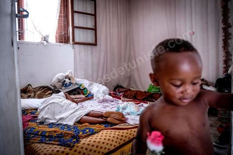 24 juin 2017 : Dans la chambre, Océane partage trois matelas posés au sol avec deux autres filles et deux bébés. Chez Océane, migrante Ivoirienne à Tunis dans un quartier populaire. Elle vit dans une maison avec 2 chambres qu'elle partage avec son fils Eden et cinq autres ivoiriennes. Océane est arrivée en Tunisie en 2010 comme étudiante et est depuis 5 ans en situation irrégulière, ne lui permettant plus de travailler légalement. Il y a deux ans Eden est né, ce jeune garçon plein de joie est devenu sa raison de vivre, elle souhaite trouver un endroit pour vivre normalement et élever son fils. “J’estime que pour vivre bien Tunisie, il me faudrait entre 800 et 1000 dinars. Généralement, je suis plutôt à 350. Entre les couches et la nourriture, les dépenses sont rapides.” La jeune femme travaille de façon irrégulière : elle a quelques patrons qui l’appellent, selon leur besoin, pour faire le ménage chez eux. Une journée lui rapporte entre 25 et 30 dinars.  