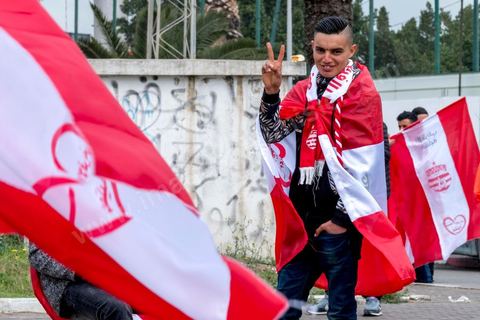 February 18, 2018: At CA’s Park A, fans gather to make their final purchases of banners and scarves before heading to the stadium for the game. In Tunis, it’s the big day—the soccer derby, the match between the league’s two current top teams and Tunis’s two flagship clubs, Club Africain (CA) versus Espérance de Tunis (EST), at the Grand Stadium of Radès in the southern suburbs of Tunis. This rematch favors CA, which controls ticket sales. Given the numerous clashes between fans and ultra groups in the stadiums—both among themselves and with the police— only 23,000 tickets are being sold (out of a capacity of 60,000), including 1,200 for EST—though only about 50 of those will be in the south stand. The match will end with a surprise 2–1 victory for CA. 