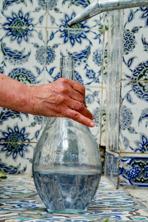 Distillation traditionnelle de fleurs de rose dans maison de la région de Nabeul au Cap Bon. L'eau et l'essence de rose proviennent de la distillation des fleurs de rose. La distillation est conduite très doucement sur le feu, l'hydrolat coule dans des Marie-Jeannes en verre. Le distillat coule légèrement tiède. 1 kg de pétale produit environ 1,5 litres d'eau de roses.