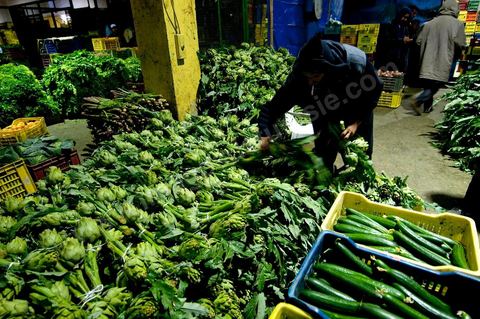 Vendeur et étales de concombres et artichauts à la Halle aux fruits et légumes du marché de gros de Tunis à El Mourouj