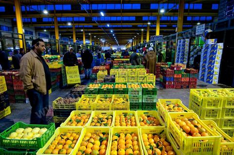 Vendeur et étales de oranges et pommes à la Halle aux fruits et légumes du marché de gros de Tunis à El Mourouj