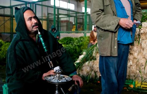 Vendeur fumant la chicha à la Halle aux fruits et légumes du marché de gros de Tunis à El Mourouj
