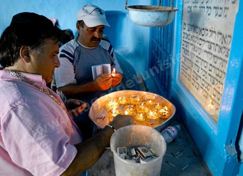 Pelerins juifs déposant des cierges et priant dans une petite synagogue bleue à Hara Sghira Erriadh durant le pelerinage juif annuel au village de Erriadh ou Hara Sghira sur l'ile de djerba