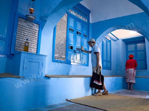 Pelerins juifs déposant des cierges et priant dans une petite synagogue bleue à Hara Sghira Erriadh durant le pelerinage juif annuel au village de Erriadh ou Hara Sghira sur l'ile de djerba