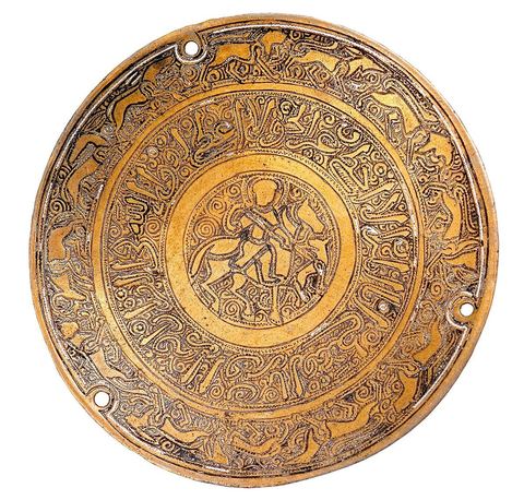 PLATEAU DE BALANCE AU CAVALIERMésopotomie (Irak),12  - 13  siècle. Cuivre et traces d'argent.La pièce, percée de trois trous de suspension, est finement ciselée. Au centre, un cavalier vu de face, à la figure nimbée d'une auréole, accompagné de son lévrier. Il est entouré de spires renforçant la position dynamique du cheval et du lévrier. Tout autour, une dernière frise en caractère cursif 'naskhi', aux courbures accentuées, tapissée des mêmes spires. Elle livre, partiellement, un verset du Coran se référant au thème de la 'juste balance'. Sur la dernière frise, une sphinge, corps de félin ailé et tête de femme, et une suite d'animaux passant, liés au thème de la chasse: lion, guépard, cerfs, antilope, lévrier.Si la relation est évidente entre la balance et le passage du Coran, l'association entre divers thèmes, tels que la mesure, la parole divine, une créature fabuleuse, un cavalier auréolé et une scène de chasse paraît incongrue. Elle trouve cependant sa cohérence dans la dimension ornementale d'une oeuvre plaisante au regard, et la réussite d'un beau mouvement dynamique. Dans de nombreuses pièces de l'art arabe et islamique, il ne faut chercher ni symbole, ni 'horreur du vide', mais souvent, simplement, un décor pour le décor, au sens le plus fort d'un art pour l'art