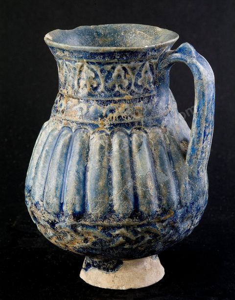 PICHET MOULÉIraq ou Perse, époque abbaside, 8  - 9  siècle.Cette céramique moulée à la panse cannelée et au col muni d'anneaux dérive directementd'un modèle en métal.