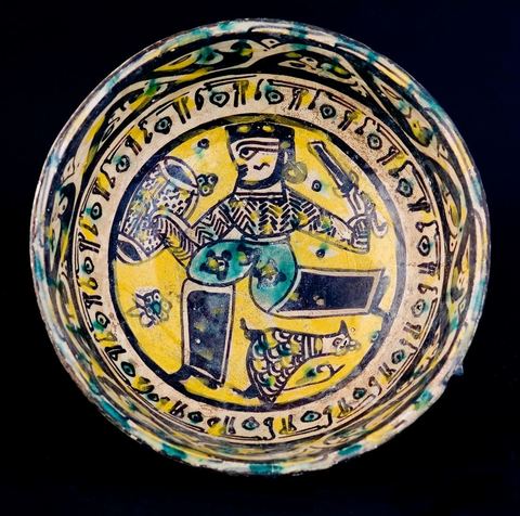 COUPE AU GUERRIER.Khorassan, Nichapour,  10 - 11  siècleBuste de face, le guerrier se présente de profil, tenant glaive et bouclier.Bordure circulaire graphique et rinceaux de demi-palmettes.