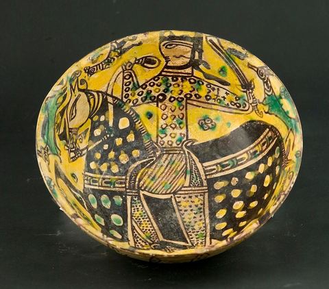 COUPE À DÉCOR DE CAVALIERKhorassan,Nichapour 10 - 11  siècleCoupe creuse caractéristique des céramiques de Nichapourà thème central. Un cavalier tenant une épée sur fond jaune peuplé de quadrupèdes et de volatiles. L'ample harnachement de la monture, traité dans un noir-brun intense et parsemé de points ocellés, suggèreou un thème astral ou l'évocation d'un  personnage de haut rang.