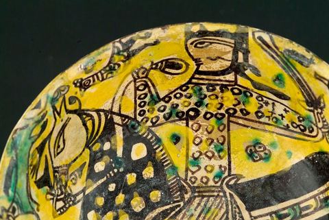 COUPE À DÉCOR DE CAVALIERKhorassan,Nichapour 10 - 11  siècleCoupe creuse caractéristique des céramiques de Nichapourà thème central. Un cavalier tenant une épée sur fond jaune peuplé de quadrupèdes et de volatiles. L'ample harnachement de la monture, traité dans un noir-brun intense et parsemé de points ocellés, suggèreou un thème astral ou l'évocation d'un  personnage de haut rang.