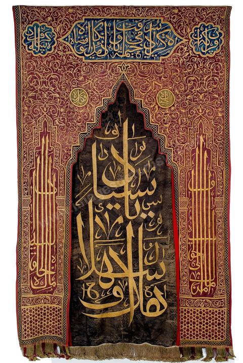 PORTIÈRE DE MOSQUÉE OTTOMANE. Turquie ottomane, 18  siècle.Décors de rinceaux, d'étoiles et de cartouches calligraphiés en 'Thuluth' formant une arcature sur piliers empruntant le modèle d'une niche de prière, le mihrab.Inscription proverbiale :'Celui qui vers le vrai se tourne, vers lui le Créateur se tourne'. Inscription sur le panneau central : 'Bienvenue aux seigneurs !'.Les inscriptions du haut sont en écriture arabe et en langue turque. La couleur rouge du fond, caractéristique des tentures ottomanes, n'est pas sans évoquer les tentures offertes par les sultans ottomans au mausolée du prophète Mohammad à Médine.