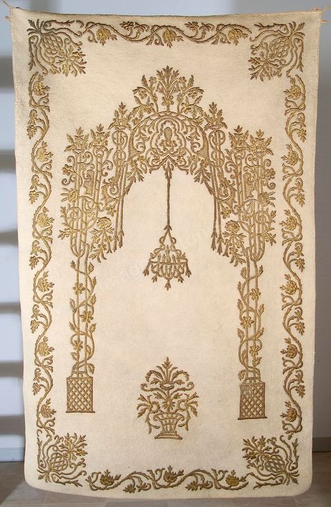 TAPIS DE PRIÈRE 'IMPÉRIAL'.Turquie, ottomane,19  siècle. Laine brodée de fil d'or. Décor 'baroque' en niche de prière et lampe suspendue symbolisant la lumière divine. La plupart des régions musulmanes ont produit des tapis de jonc, de laine ou de soie évoquant mihrab et lumière. Parmi lesquels quelques exemplaires singuliers, tel que le tapis exposé. Un tapis similaire orne la salle de prière du  Sultan Abdelhamid au palais de Dolma Bahché à Istanbul. Le verset du Coran auquel la suspention fait tradionnellement référence est tiré du chapître de La Lumière (Coran, XXIV, 35) 'Allah est la lumière des cieut et de la terre. Sa lumière est à la ressemblance d'une niche où se trouve une lampe, la lampe est dans un verre, le verre est semblable à une étoile brillante(...)'.