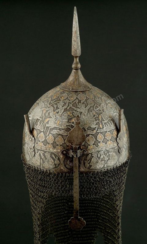 CASQUE DE CÉRÉMONIE.Perse qâdjâre,19  siècle.Acier, Or et Argent.Cette forme, en pointe, est archaïsante et se retrouve dans de nombreuses miniatures à thème guerrier. Le repertoire iconographique, scène de chasse à courre, où abondent les figures humaines et animalières, permet de situer le casque dans la série des armures à usage cérémonial, caractéristique des rites chîîtes. Apporté, vraisemblablement, par les turcs, ce genre de casque se retrouvait en Tunisie. Un casque dit, 'de Rostam' est conservé au Musée Militaire du Palais de la Rose, dans la banlieue de Tunis.	 - Musée Lella Hadria à Djerba Explore