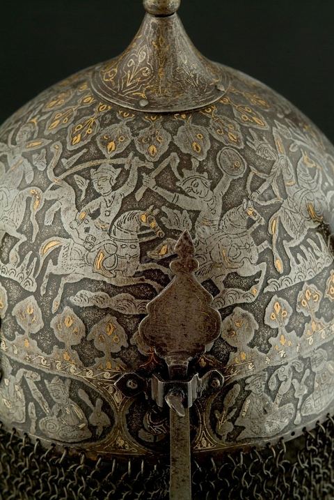 CASQUE DE CÉRÉMONIE.Perse qâdjâre,19  siècle.Acier, Or et Argent.Cette forme, en pointe, est archaïsante et se retrouve dans de nombreuses miniatures à thème guerrier. Le repertoire iconographique, scène de chasse à courre, où abondent les figures humaines et animalières, permet de situer le casque dans la série des armures à usage cérémonial, caractéristique des rites chîîtes. Apporté, vraisemblablement, par les turcs, ce genre de casque se retrouvait en Tunisie. Un casque dit, 'de Rostam' est conservé au Musée Militaire du Palais de la Rose, dans la banlieue de Tunis.	 - Musée Lella Hadria à Djerba Explore