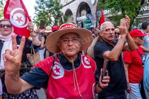 Tunis, Tunisie – 20 août 2026. Des manifestants défilent dans le centre de Tunis contre le président Kaïs Saïed, appelant à son départ et réclamant davantage de libertés politiques et la libération de détenus et opposants. Portraits du président barrés du slogan « DÉGAGE », drapeaux tunisiens et pancartes accompagnent la manifestation. La mobilisation intervient dans un contexte de mécontentement social croissant après plusieurs semaines de fortes chaleurs, de coupures d’eau et d’électricité et de difficultés d’accès à certains médicaments et produits essentiels.