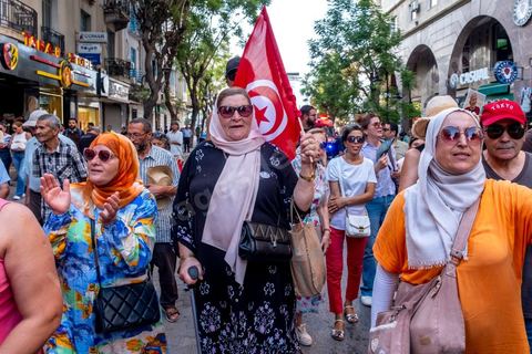 Tunis, Tunisie – 20 août 2026. Des manifestants défilent dans le centre de Tunis contre le président Kaïs Saïed, appelant à son départ et réclamant davantage de libertés politiques et la libération de détenus et opposants. Portraits du président barrés du slogan « DÉGAGE », drapeaux tunisiens et pancartes accompagnent la manifestation. La mobilisation intervient dans un contexte de mécontentement social croissant après plusieurs semaines de fortes chaleurs, de coupures d’eau et d’électricité et de difficultés d’accès à certains médicaments et produits essentiels.