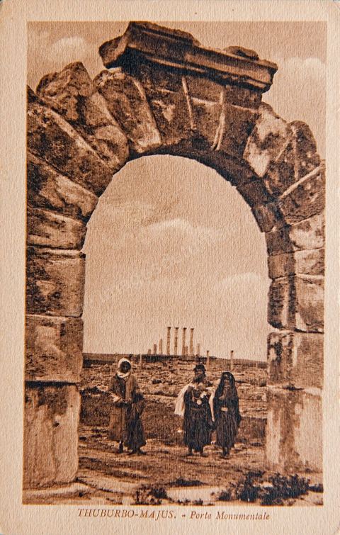 Porte monumentale avec femmes en tenue traditionnelle sur le Site archéologique romain de Thuburbo Majus - Carte postale ancienne Tunisie