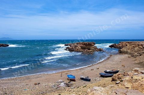 La côte d'El Haouaria à la pointe du Cap Bon, falaise, mer et montagnes. Baie avec plage et barques de pêcheurs.