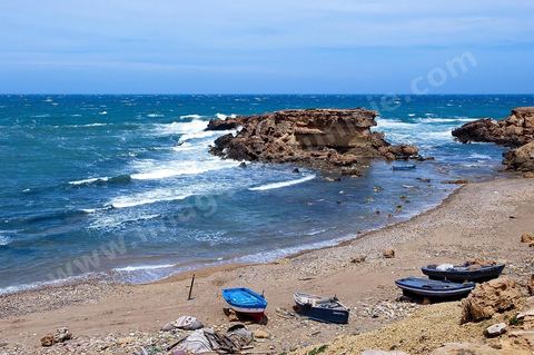 La côte d'El Haouaria à la pointe du Cap Bon, falaise, mer et montagnes. Baie avec plage et barques de pêcheurs.