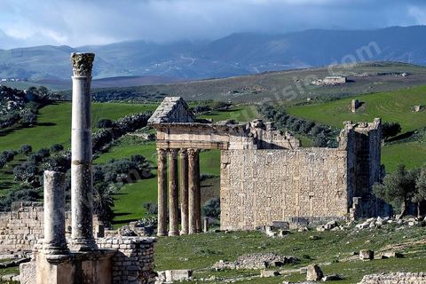 Capitole de Dougga et son majestueux temple. Le site de Dougga, classé au patrimoine mondial de l'UNESCO, Situé sur un éperon dominant la riche vallée de la Mejerdah, le site s'étend sur plusieurs dizaines d'hectares et couvre plusieurs ères historiques. L’excellent état de conservation de la plupart des monuments qui le composent dont certains, tels le capitole ou le théâtre, ont été « remis sur pied » au cours d’une campagne menée au lendemain de la première guerre mondiale par des prisonniers de guerre.