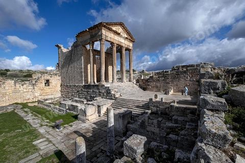 Capitole de Dougga et son majestueux temple. Le site de Dougga, classé au patrimoine mondial de l'UNESCO, Situé sur un éperon dominant la riche vallée de la Mejerdah, le site s'étend sur plusieurs dizaines d'hectares et couvre plusieurs ères historiques. L’excellent état de conservation de la plupart des monuments qui le composent dont certains, tels le capitole ou le théâtre, ont été « remis sur pied » au cours d’une campagne menée au lendemain de la première guerre mondiale par des prisonniers de guerre.