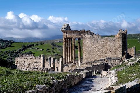 Capitole de Dougga et son majestueux temple. Le site de Dougga, classé au patrimoine mondial de l'UNESCO, Situé sur un éperon dominant la riche vallée de la Mejerdah, le site s'étend sur plusieurs dizaines d'hectares et couvre plusieurs ères historiques. L’excellent état de conservation de la plupart des monuments qui le composent dont certains, tels le capitole ou le théâtre, ont été « remis sur pied » au cours d’une campagne menée au lendemain de la première guerre mondiale par des prisonniers de guerre.