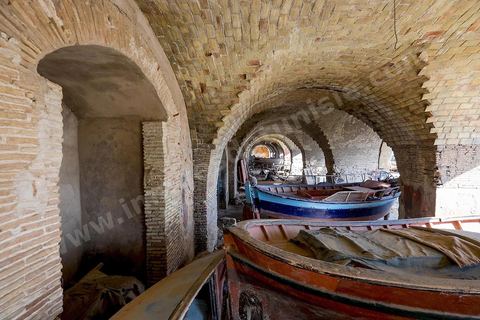The Andalusian port of Ghar El Melh in the city center. A harbor flanked by three piers; an arsenal once adjoined the port, now partially in ruins—today, only a few vaulted shops remain. A fishing port opening onto the sea and the lake.