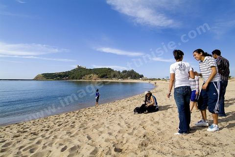 Adolescents sur la plage de Tabarka avec au fond la colline du fort génois