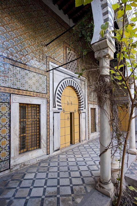 Patio à jardin du Dar Othman palais de la medina de Tunis - porte jaune ancienne et mur de céramiques