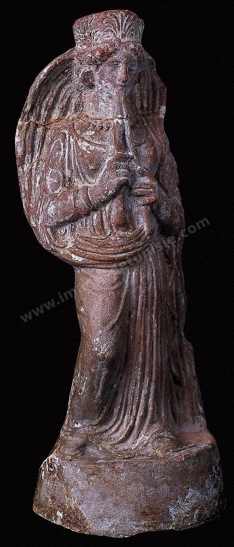 Figurine en terre cuite représentant une femme jouant de la double flûte. Elle porte une tunique longue te un manteau formant voile autour de sa tête, un diadème à palmette et des bijoux (H. 23 cm, nécropole de Borj Jedid, Carthage, IVème siècle avant JC, musée de Carthage).