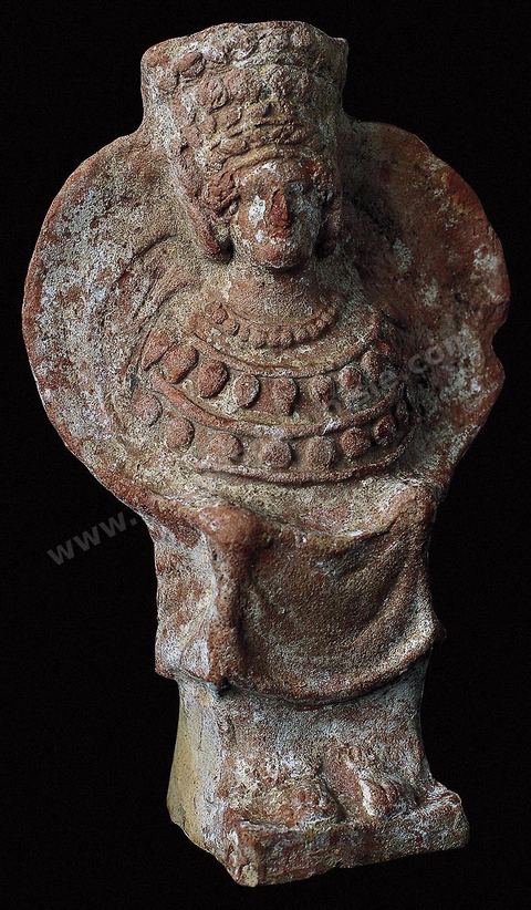 A seated terracotta goddess, her bust surrounded by a circular veil and her head adorned with an enormous diadem. She wears long earrings, and a heavy pectoral made of necklaces covers her chest. This profusion of ornamentation appears to have symbolic significance (H. 18 cm, Punic necropolis of Byrsa, 4th century BCE, Carthage Museum).