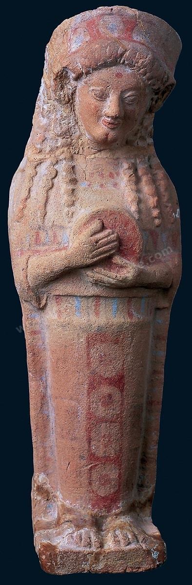 Déesse au tympanon. Cette figurine en terre cuite a l'attitude hiératique egyptienne mais l'ornementation du vêtement et la richesse de ses couleurs sont autant d'emprunts à l'Orient. Le traitement de la chevelure et le diadème qui la coiffe évoquent la Grèce d'Asie (H. 33 cm, nécropole d'Ardh el Morali, fin du VII ème siècle avant JC, musée de Carthage).