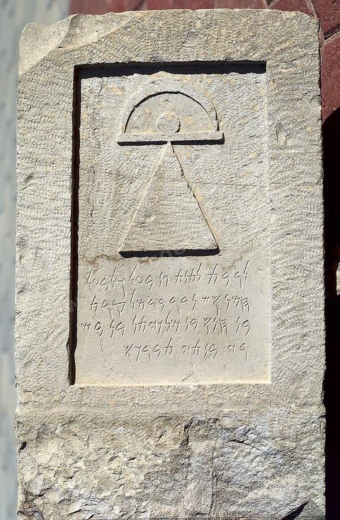 A votive stele made of grayish limestone that stands out from most other steles due to its rectangular shape, its design, the absence of a pediment and acroteria, as well as any other decoration aside from the so-called “Tanit symbol,” which is not incised but carved in bas-relief. While the triangle with a circle resting on its apex is certainly present, the bar above it ends in a semicircle—evoking a crescent—rather than taking on the fairly common anthropomorphic form created by the addition of connected arms. The dedication is in honor of Tanit and her consort, Lord Baal Hammon. This stele confirms the Punic people’s preference for geometric figures and symbolic imagery: the so-called “sign of Tanit” resembles the Egyptian “ankh” and shares its vital significance. Although we possess more than 7,000 stelae (including 1,000 at the Louvre) and more than 6,000 dedications, depictions of Tanit and Baal Hammon in forms other than their symbols are extremely rare (H. 59 cm, W. 33.5 cm, Tophet, Carthage, 4th century BCE, Carthage Museum).
