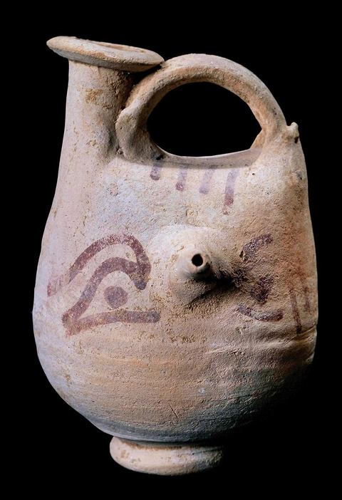 Punic terracotta bottle-shaped vase decorated with a painted human mask in which the nose serves as a nipple: the shape and decoration serve as a charm to ward off evil and are believed to protect the child from harm (H.‑11‑cm, Punic necropolis of Carthage, 3rd century B.C., Bardo Museum). Punic section—Bardo Museum