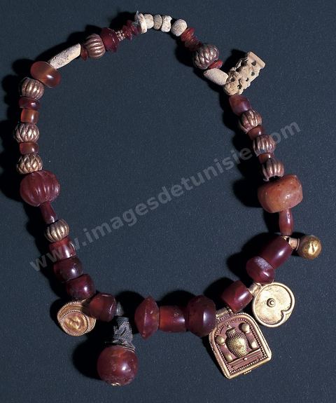 Collier punique composé d’amulettes et de divers éléments : pendentif en or à décor égyptisant, discoïdes en or, perles en cornaline, ambre et pâte siliceuse émaillée (nécropole de Dermech, fin du VIIe début du VIe siècle av. J.-C., musée du Bardo) Section punique - musée du Bardo