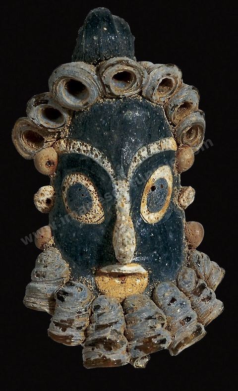 Masques-pendentifs en pâte de verre de différentes couleurs (gris et bleu, blanc et noir, bleu et jaune). Fortement typés, ils ont des yeux exorbités dont l’iris est dilaté et des cheveux et une barbe souvent calamistrés en forme de tortillons. Une bélière permet de les enfiler dans des colliers ou de les porter comme pendentifs. Leur grande vogue se situe aux IVe‑et‑IIIe‑siècles (H.4‑à 6‑cm, nécropoles de‑Carthage, IVe-IIIe siècle av. J.-C., musées du Bardo). Section punique - musée du Bardo