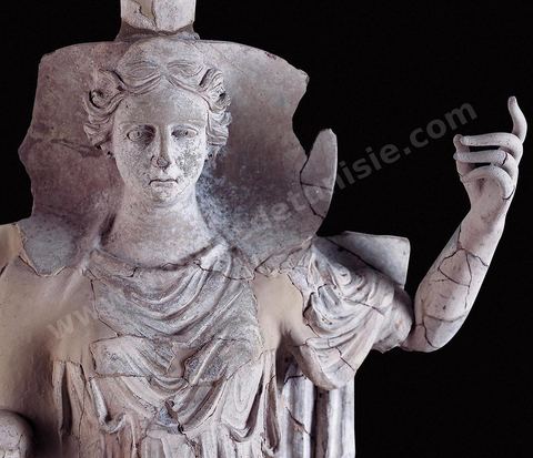 Statue de Déméter en terre cuite, presque grandeur nature, assise sur un trône en posture divine, vêtue d’une robe plissée, la tête coiffée d’une tiare cylindrique en forme de boisseau ou polos, et encadrée d’un voile rigide évoquant une conque. Son culte et celui de Coré furent officiellement introduits à Carthage en 396‑av. J.-C. pour réparer la profanation d’un de ses temples à Syracuse. Très présente dans les sanctuaires ruraux du Cap Bon, on l’y trouve tantôt associée à Baal Hammon et Tanit , tantôt accompagnée de ses parèdres Coré et Pluton, comme à Korba. Elle semble porter la réminiscence d’un modèle dû aux coroplathes siciliens des IVe-IIIe siècles av. J.-C. ( sanctuaire rural près de Korba , fin‑IVe-début IIIe siècle av. J.-C., musée du Bardo ).