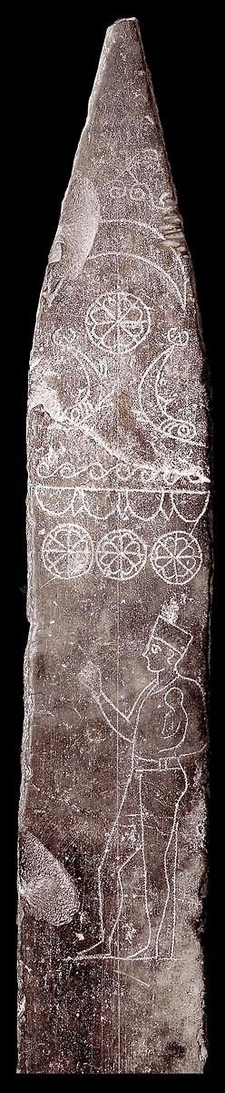 Stèle en calcaire, en forme d’obélisque, portant un décor gravé représentant un prêtre ( kohen ), vêtu comme ceux d’Égypte d’une robe de lin transparente et coiffé du bonnet cylindrique des kohanim. Sa main droite est levée dans un geste de prière, et il tient sur son bras gauche un enfant qu’il s’apprête à sacrifier selon la conception traditionnelle du tophet, ou à «restituer» à la divinité selon des interprétations récentes. Le fronton de la stèle est orné du disque solaire et du croissant ( symboles de Baal et de Tanit ) surplombant deux dauphins qui évoquent l’Océan céleste. Cette stèle est l’un des arguments principaux de ceux qui pensent que des sacrifices d’enfants étaient effectués dans le tophet ( H. 120 cm, tophet de Carthage, IIIe siècle, musée du Bardo ). Section punique - musée du Bardo