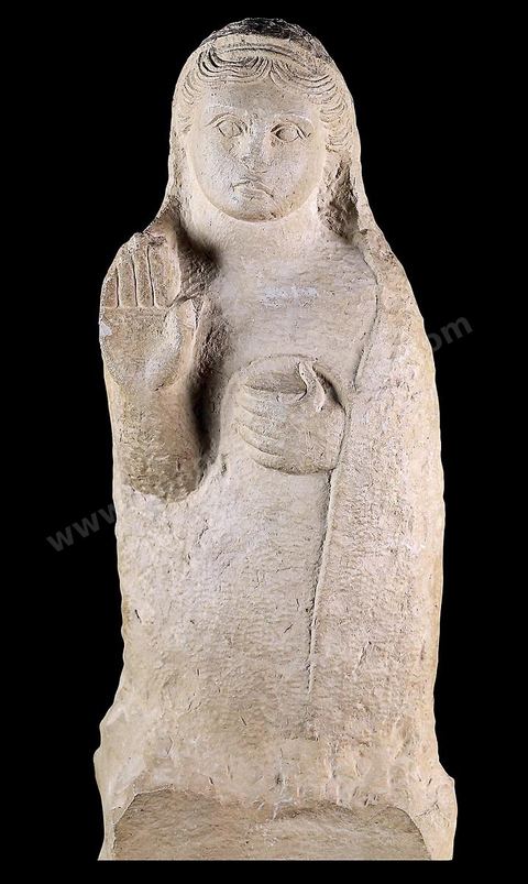 Stèle funéraire en forme de statue figurant un personnage féminin debout sur un piédestal. Un voile posé sur l’arrière de la tête enveloppe presque tout le corps‑; la chevelure soigneusement dessinée dénote une influence grecque archaïque. La main droite est levée en signe de prière, la gauche tient une pyxide. Cette stèle était érigée au-dessus du puits funéraire d’une tombe de Carthage ( H. 73,5‑cm, nécropole de Borj Jedid, Carthage, IVe-IIIe siècles av. J.-C., musée du Bardo ).scetion punique - musée du Bardo